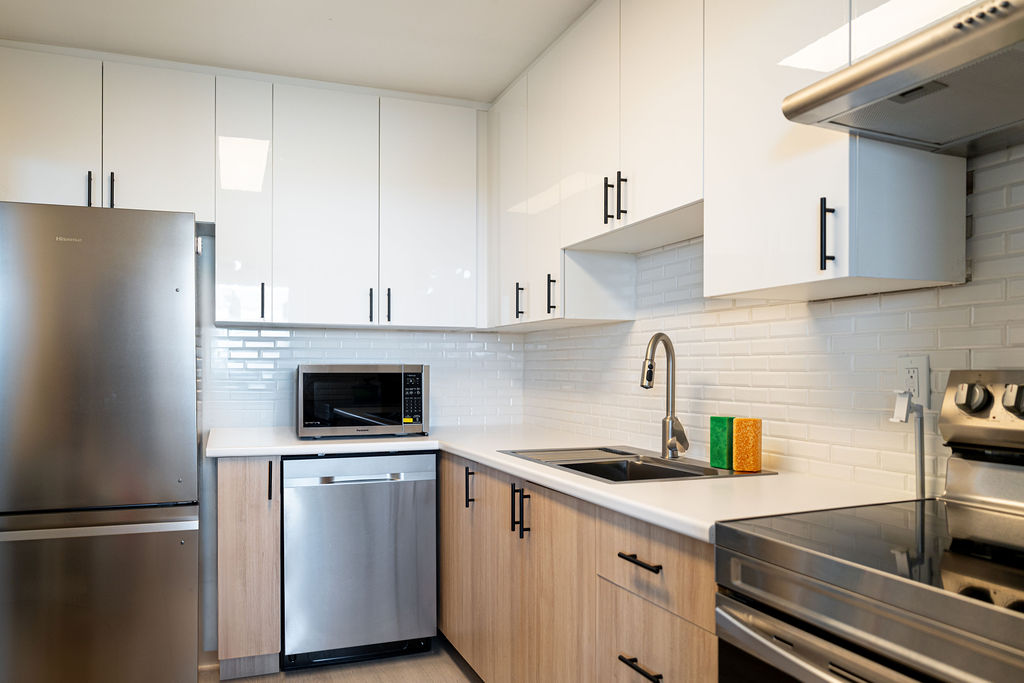 Modern all-white flat-panel European style kitchen with minimalist handleless cabinets in a bright showroom setting